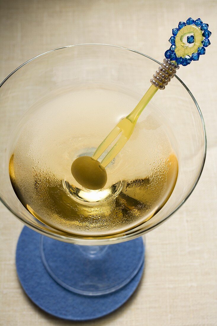 Martini with green olive on cocktail fork