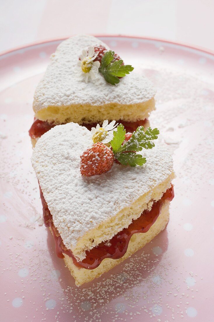 Heart-shaped cakes with jam, icing sugar, wild strawberries