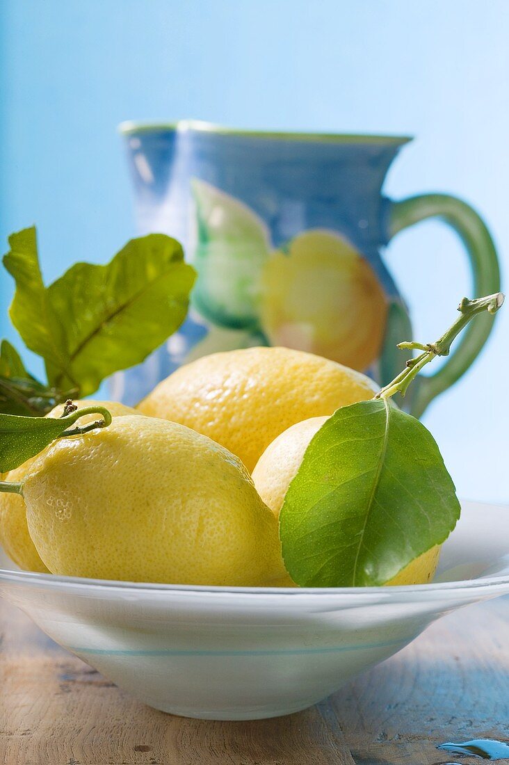 Fresh lemons with leaves in bowl