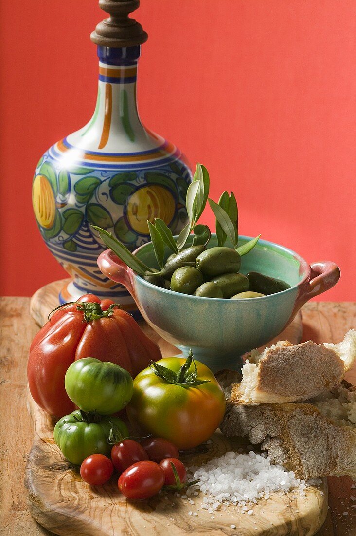 Frische Tomaten, Oliven, Brot, Salz und Keramikkrug