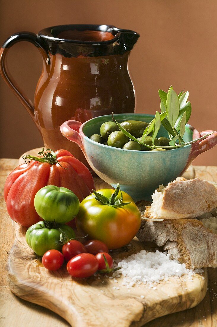 Frische Tomaten, Oliven, Brot, Salz und Tonkrug