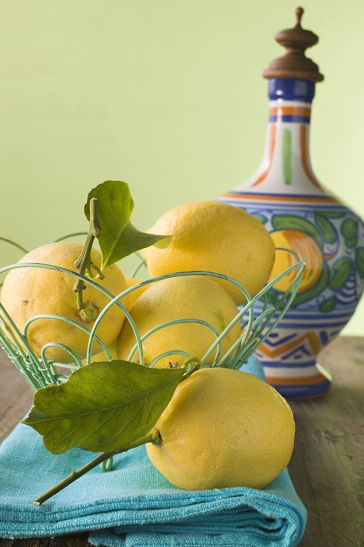 Fresh lemons with leaves in wire basket