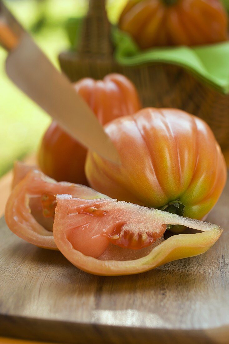 Frische Tomaten vor und im Korb mit Messer