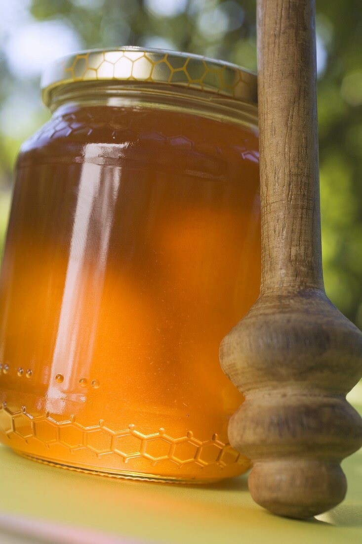 Jar of honey with honey dipper on table in the open air