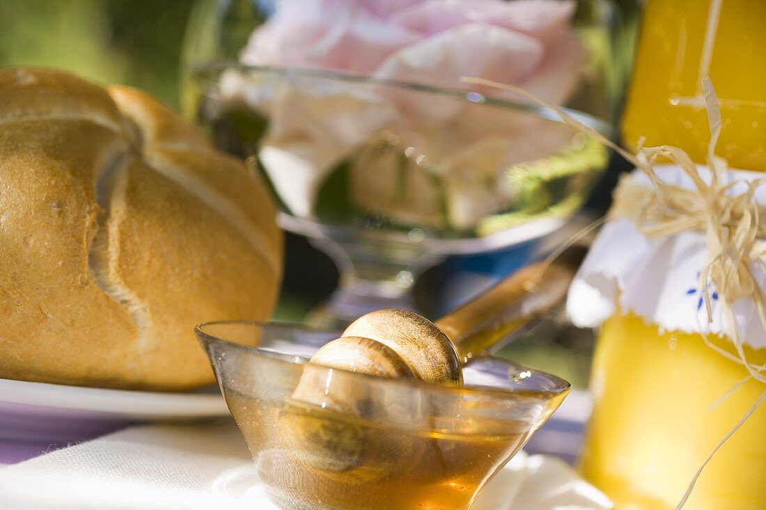 Honey in glass bowl beside bread roll