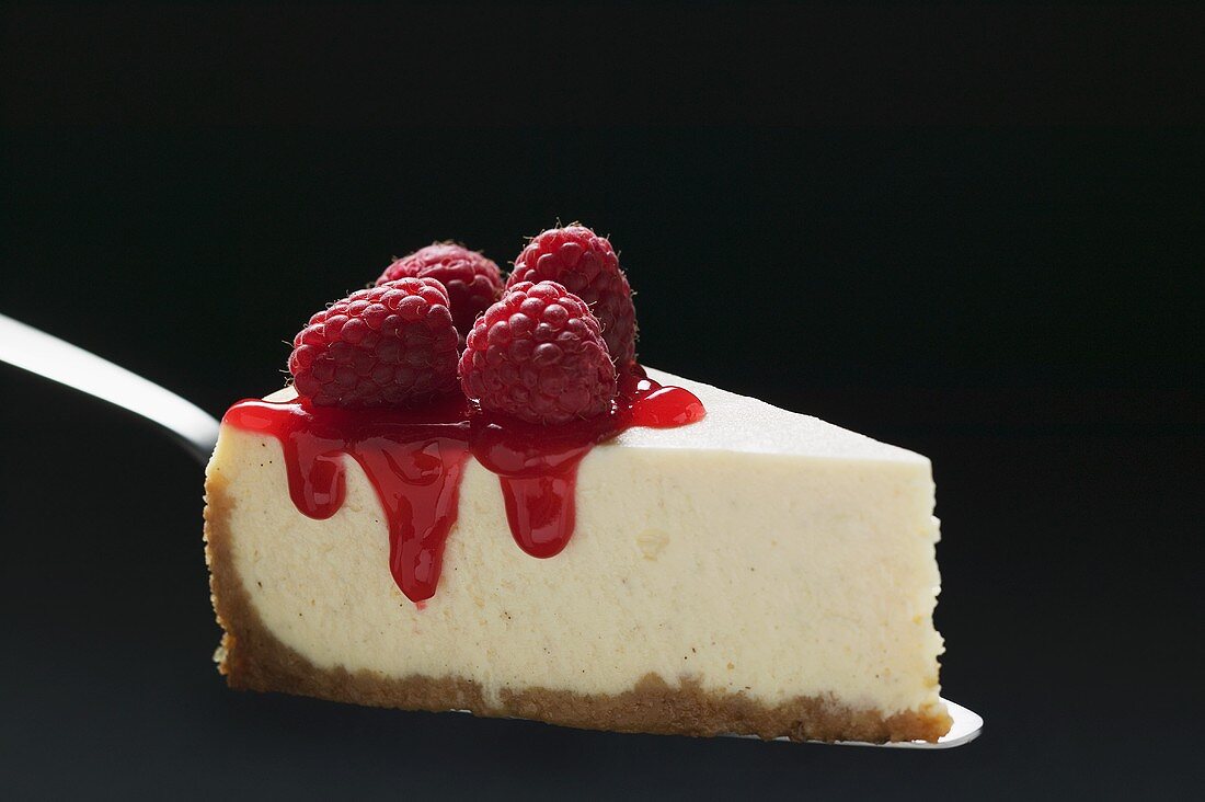 Slice of cheesecake with raspberries on cake server