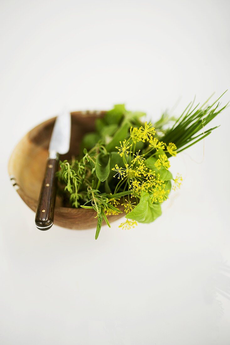 Assorted herbs in wooden bowl with knife