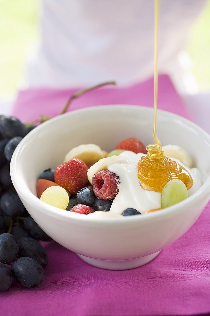 Honey running onto fruit muesli with yoghurt