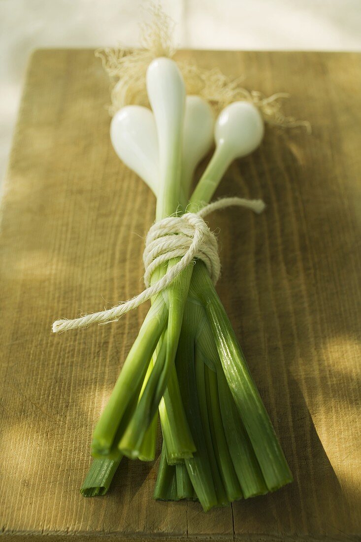 A bunch of spring onions on chopping board