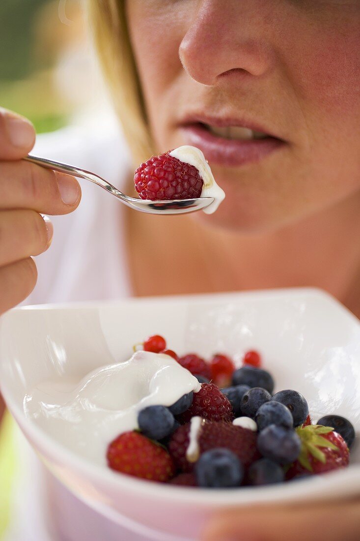 Woman eating berry muesli with yoghurt