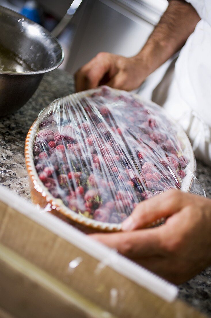 Covering berry dessert with cling film