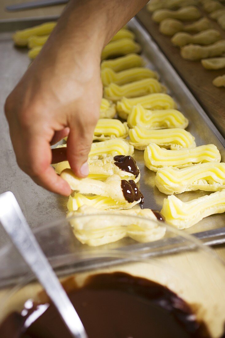 Eclairs mit Cremefüllung und Schokolade auf Backblech legen