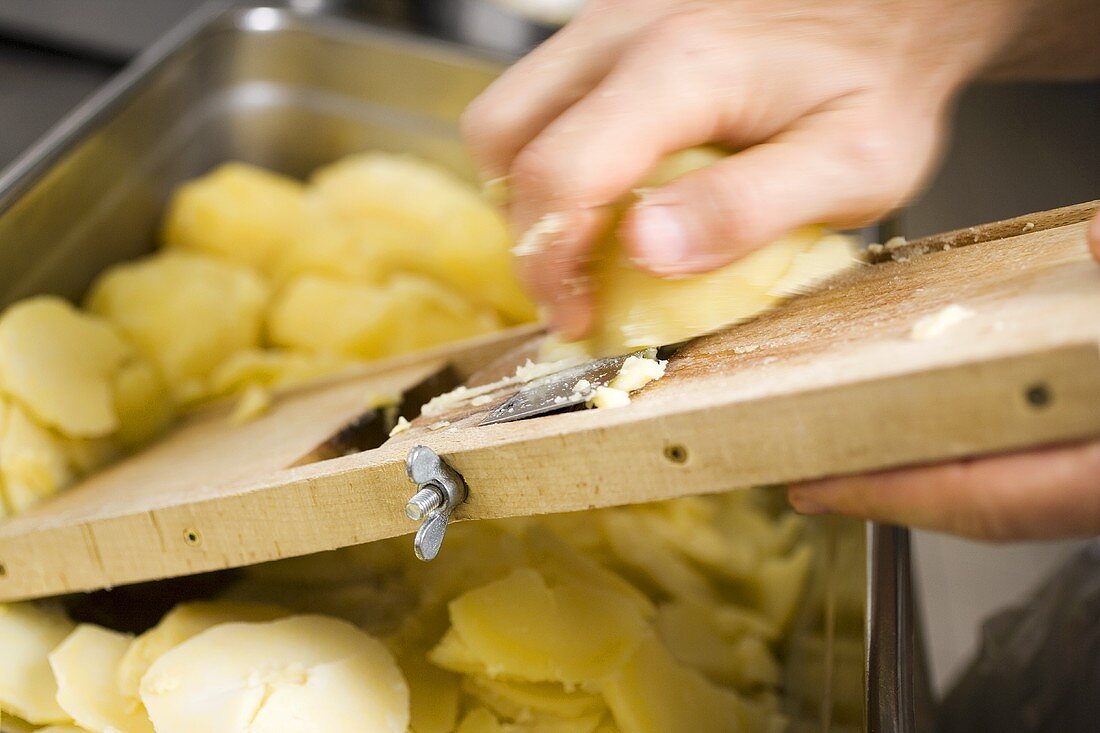 Gekochte Kartoffeln mit Reibe in Scheiben schneiden