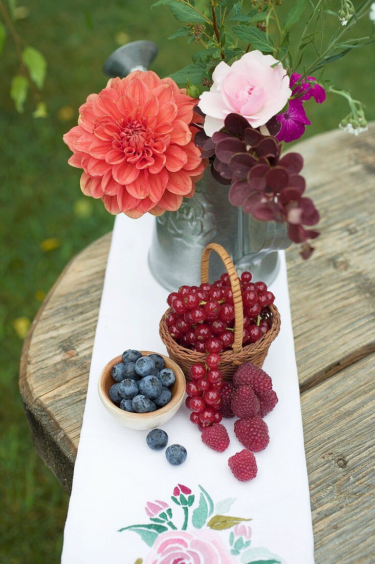 Frische Beeren und Blumenstrauss auf rustikalem Tisch