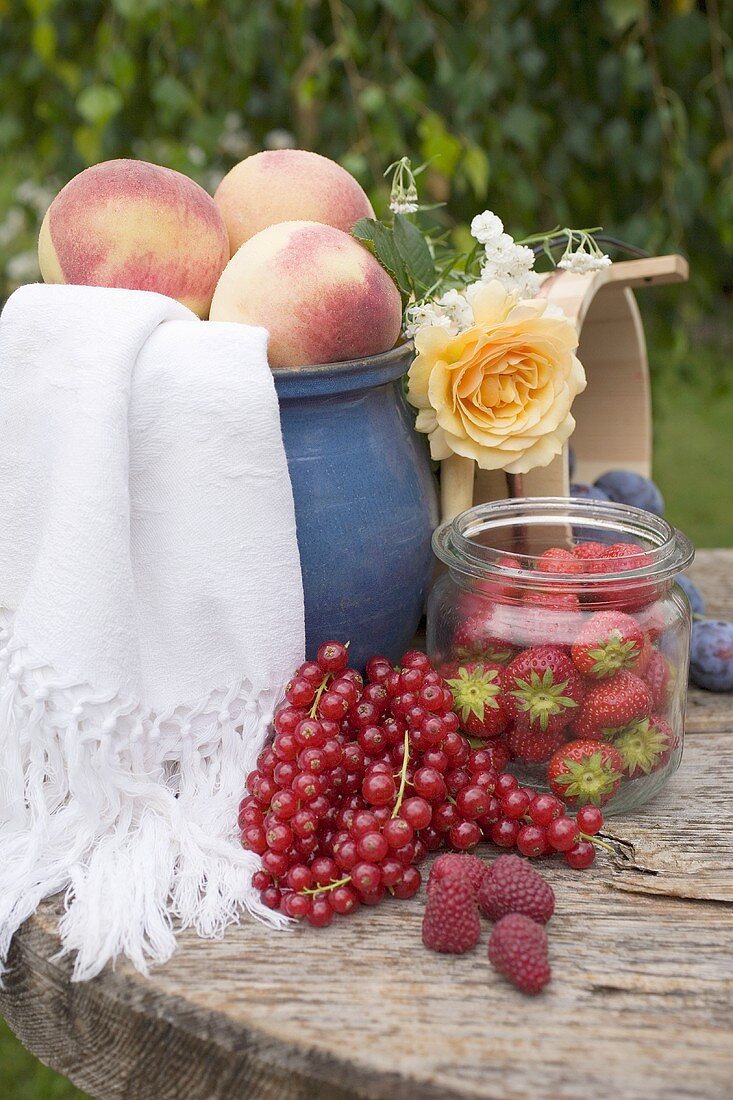 Pfirsiche und Beeren auf Tisch im Garten