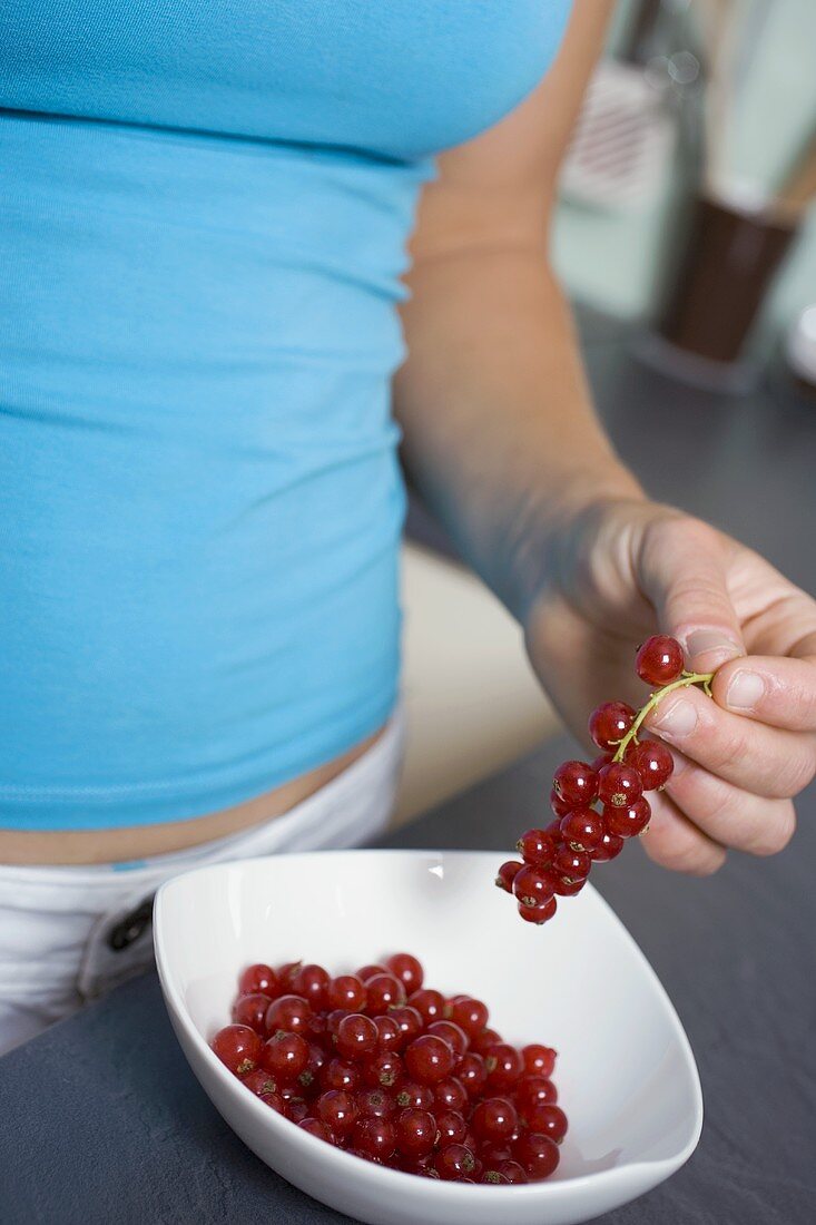 Frau nimmt rote Johannisbeeren aus Schale