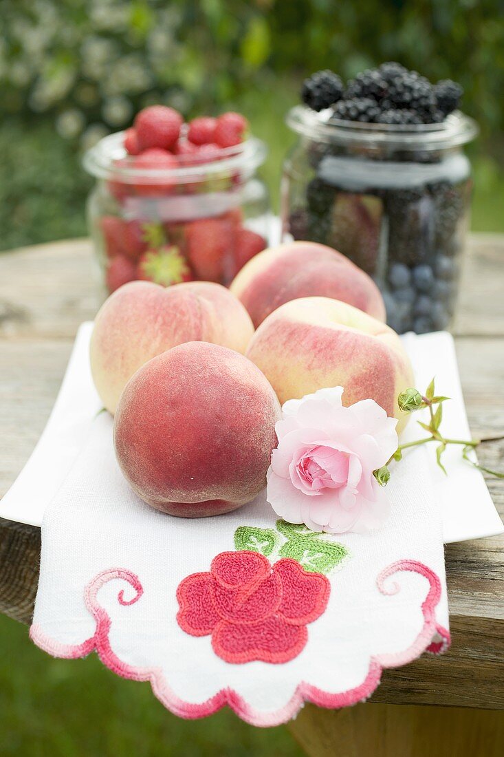 Fresh peaches and berries on table out of doors