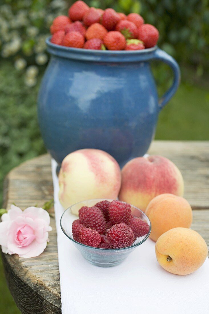 Apricots, peaches and berries on table out of doors