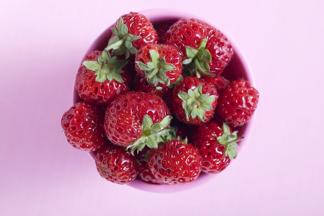 Fresh strawberries in pink beaker from above