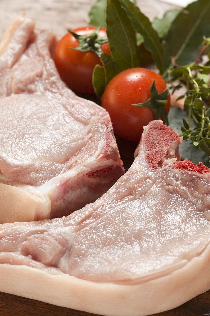 Raw pork chops, fresh herbs and tomatoes