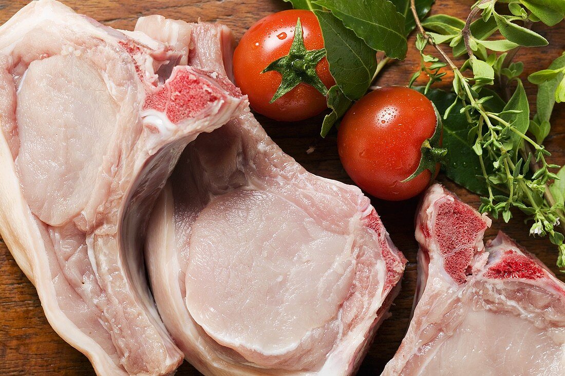 Raw pork chops, fresh herbs and tomatoes