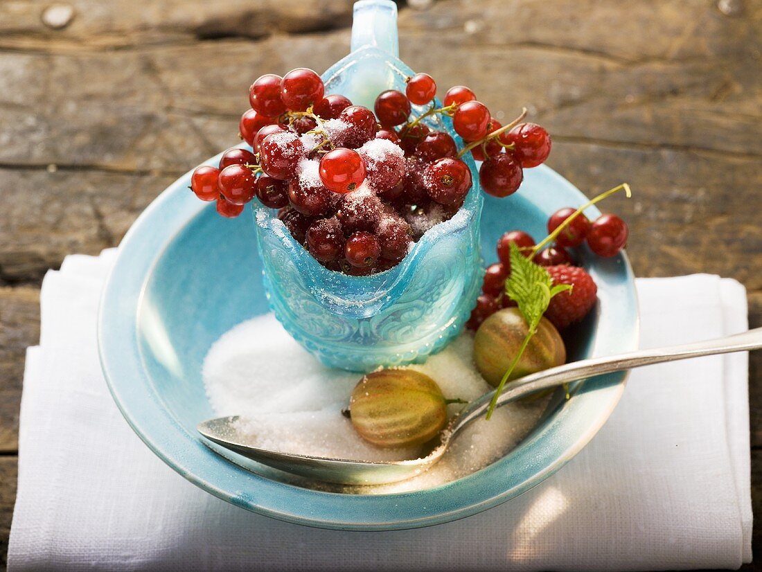 Redcurrants in glass jug, sugar, gooseberries, raspberry
