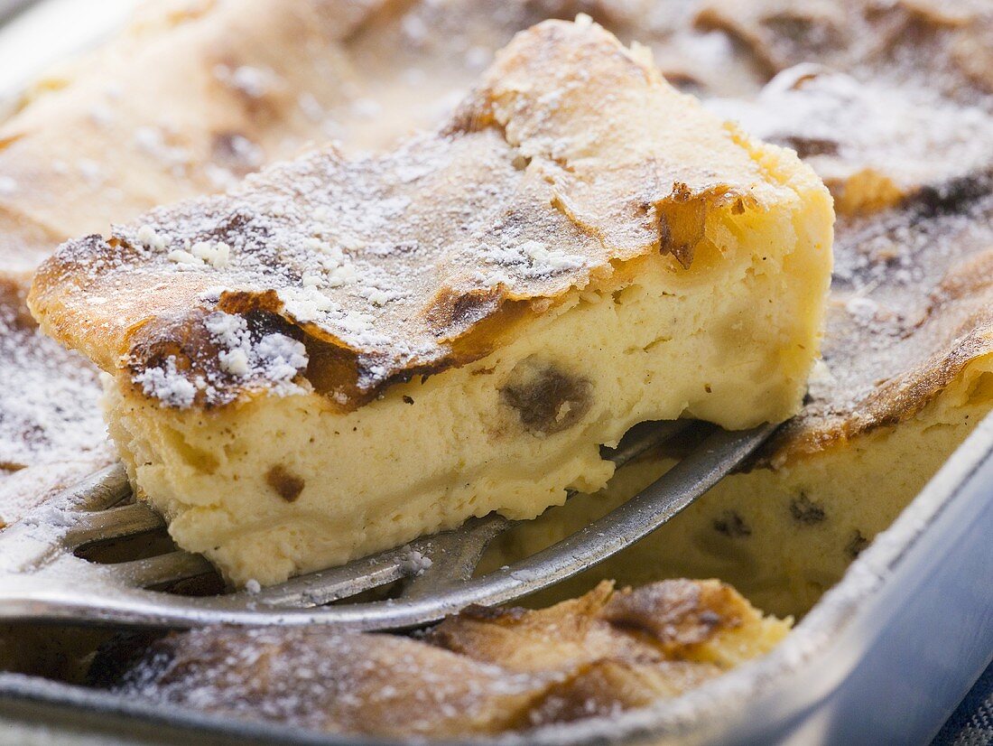 Curd cheese strudel in baking tin with piece on server