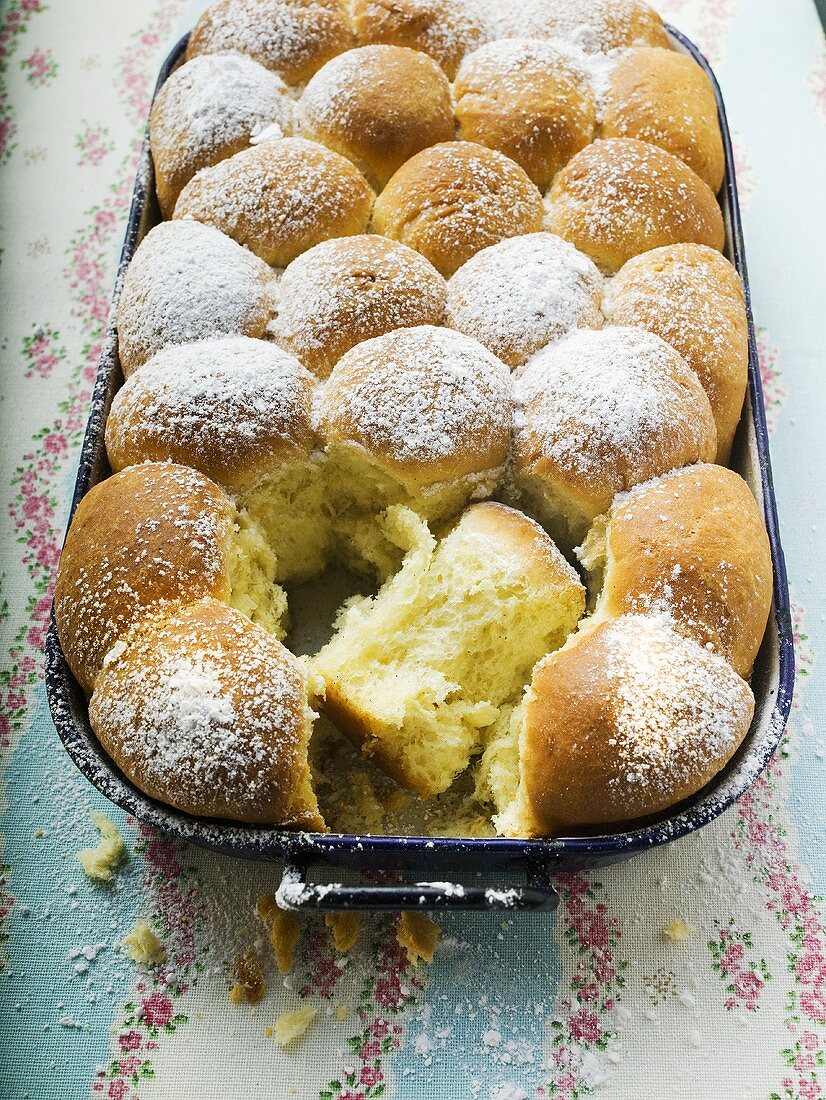 Buchteln (sweet yeast rolls) with icing sugar in baking tin