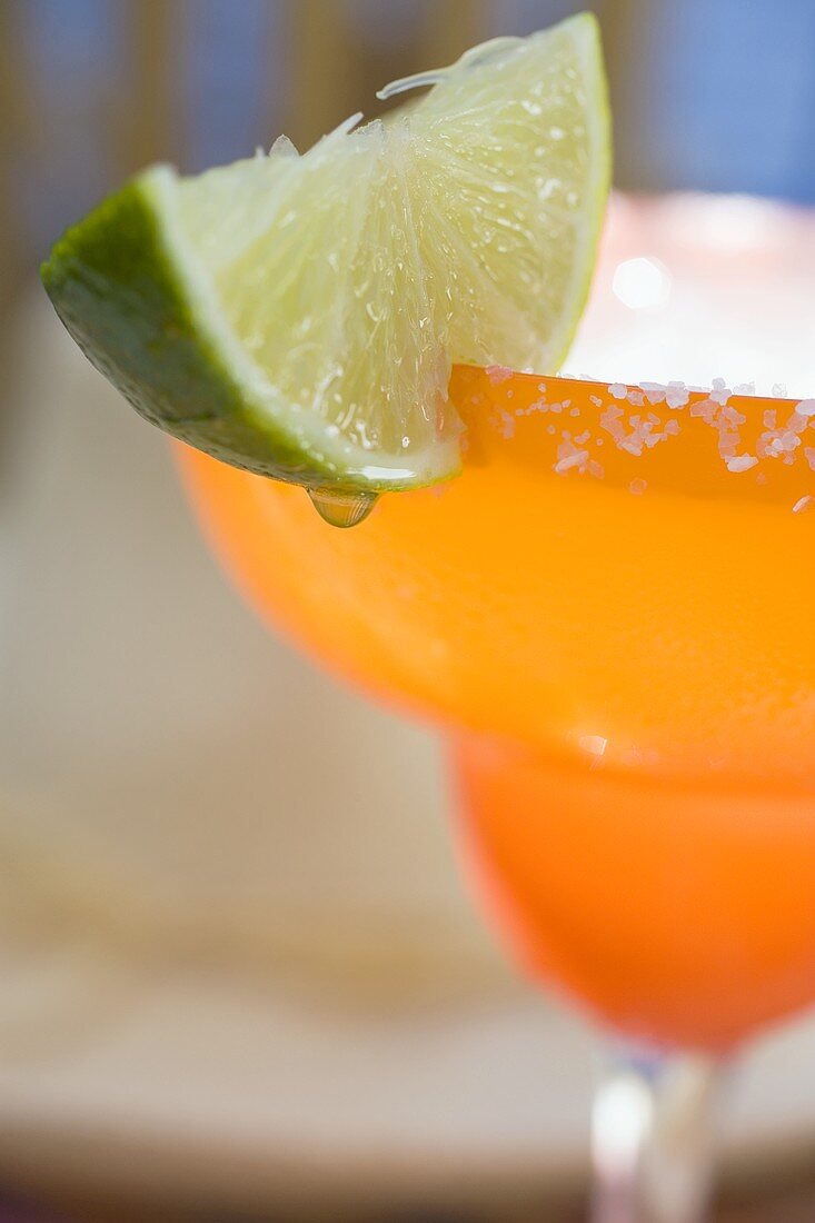 Margarita with wedge of lime in orange glass