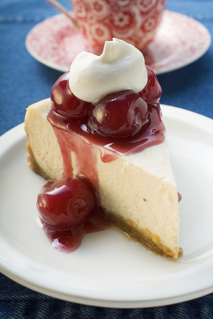 Stück Käsekuchen mit Kirschen und Sahne