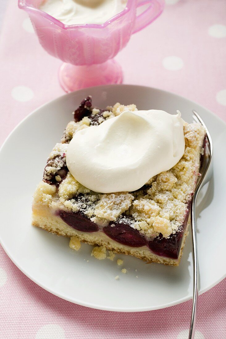 Ein Stück Kirsch-Streusel-Kuchen mit Sahne