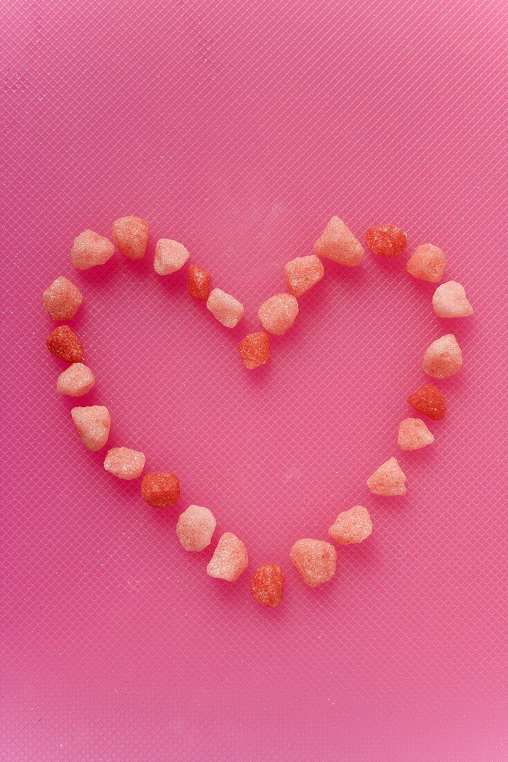 Small pink sweets arranged in a heart shape (outline)