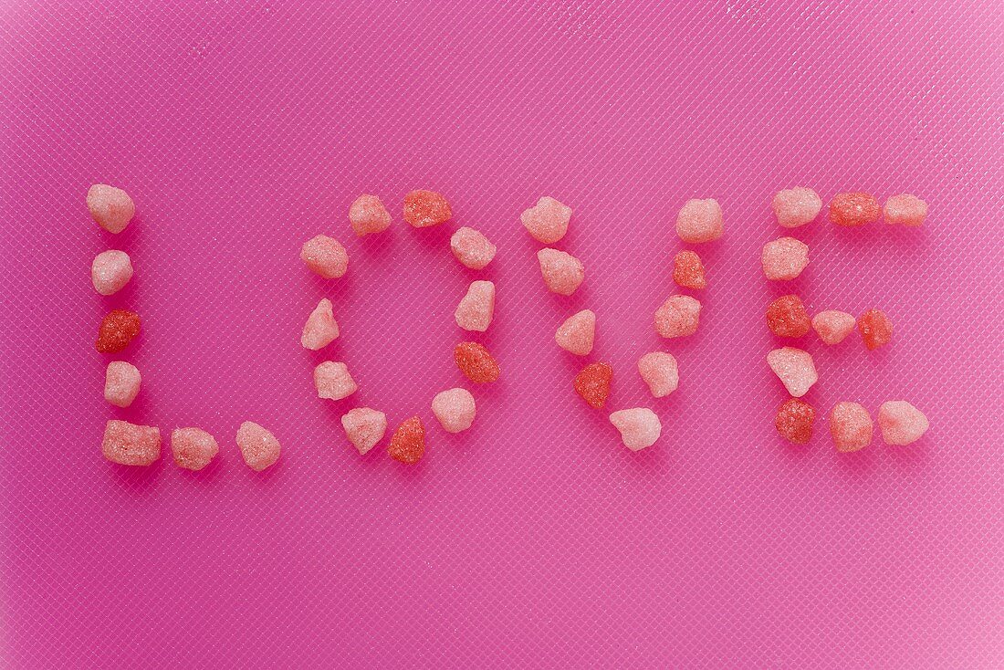 Schriftzug 'Love' aus kleinen rosa Zuckerbonbons