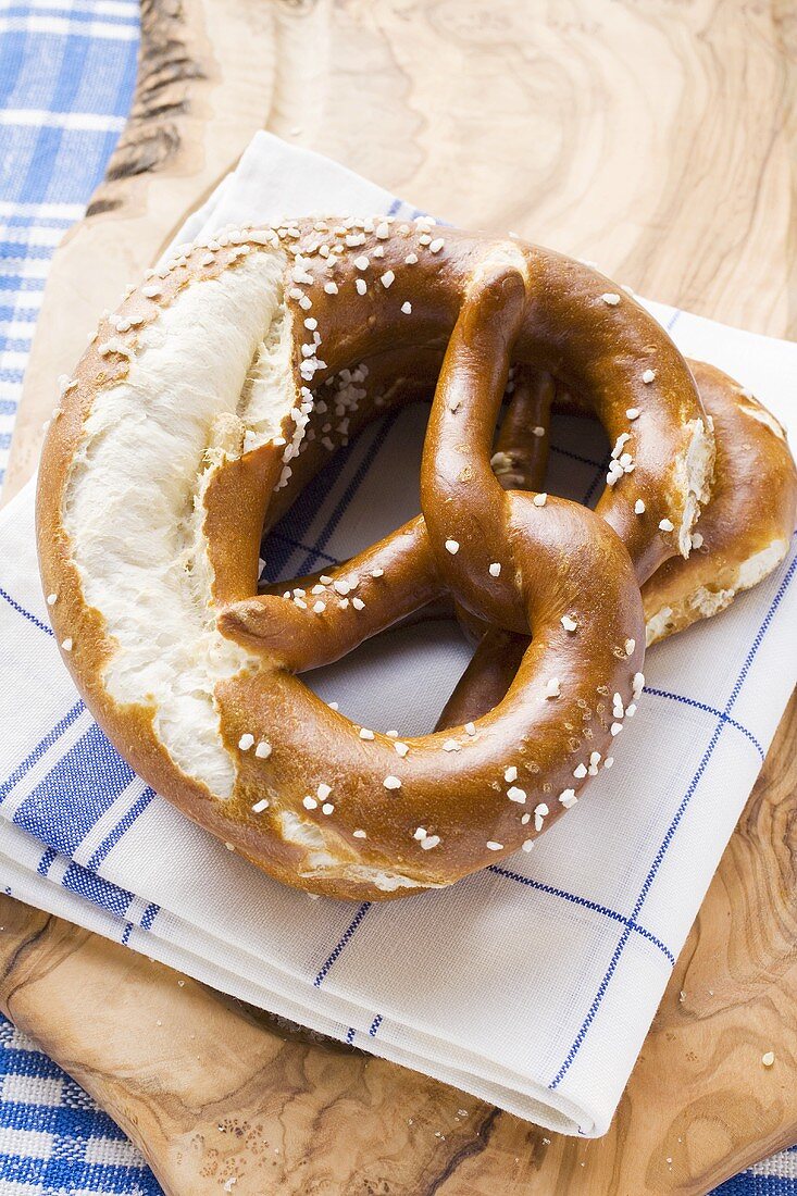 Soft pretzels on tea towel on chopping board