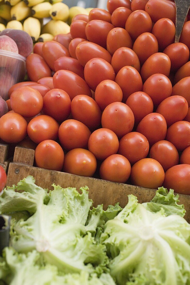 A heap of plum tomatoes in a crate at a market