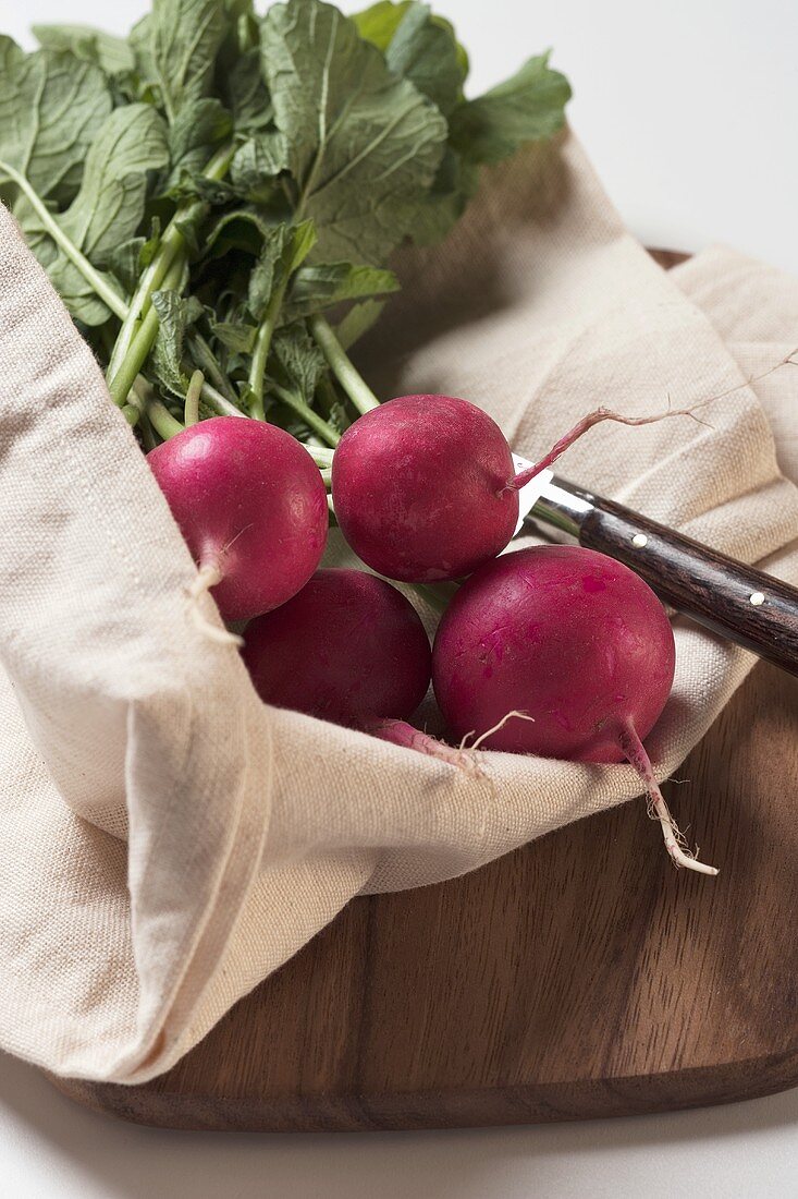 Radishes with linen sack on chopping board