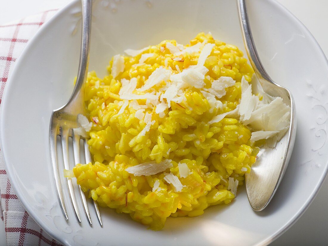 Saffron risotto with Parmesan on white plate with cutlery