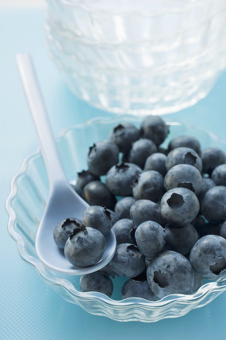 Fresh blueberries in glass bowl with spoon