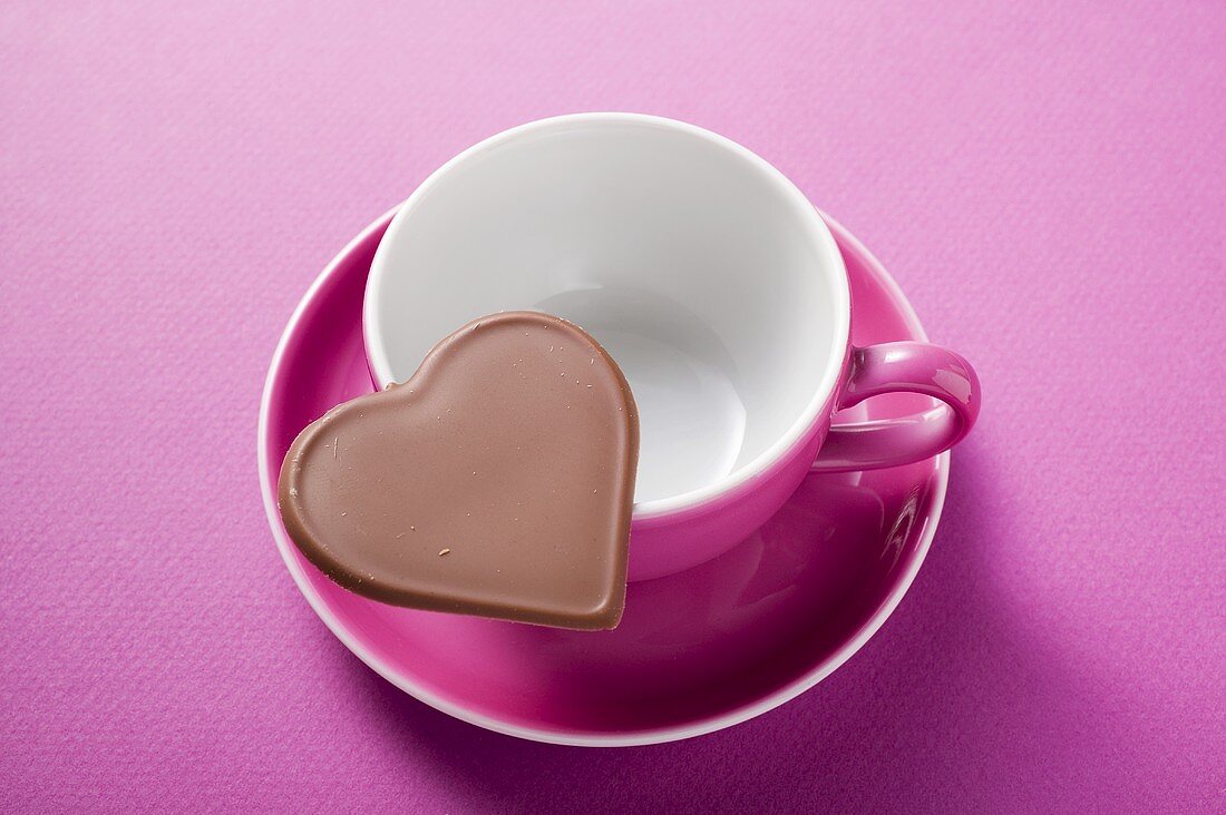 Chocolate heart on pink coffee cup