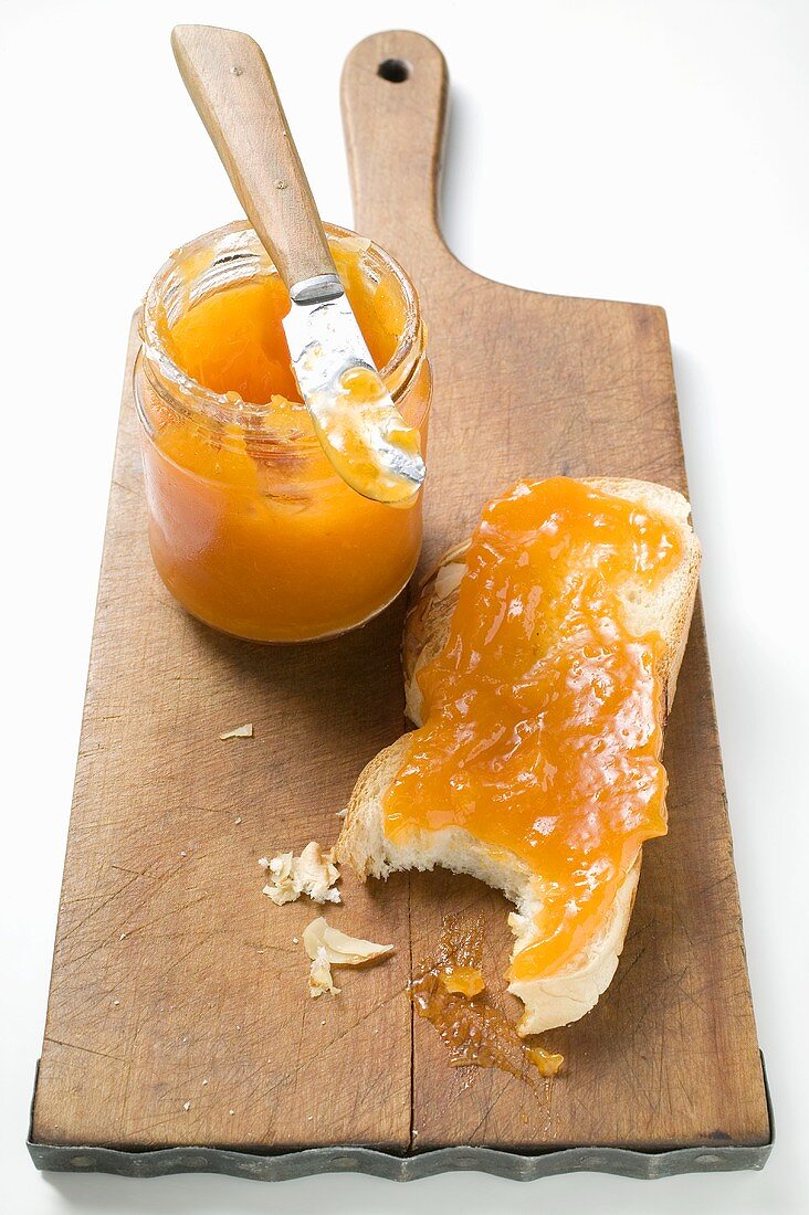 Slice of bread plait with apricot jam beside jam jar