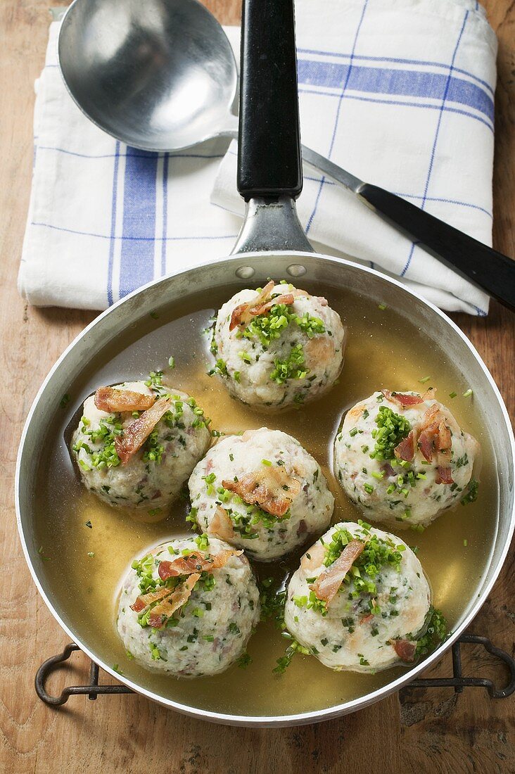 Clear broth with bacon dumplings in frying pan