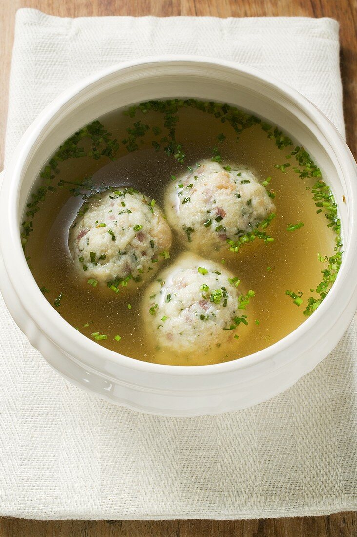 Clear broth with bacon dumplings in soup bowl