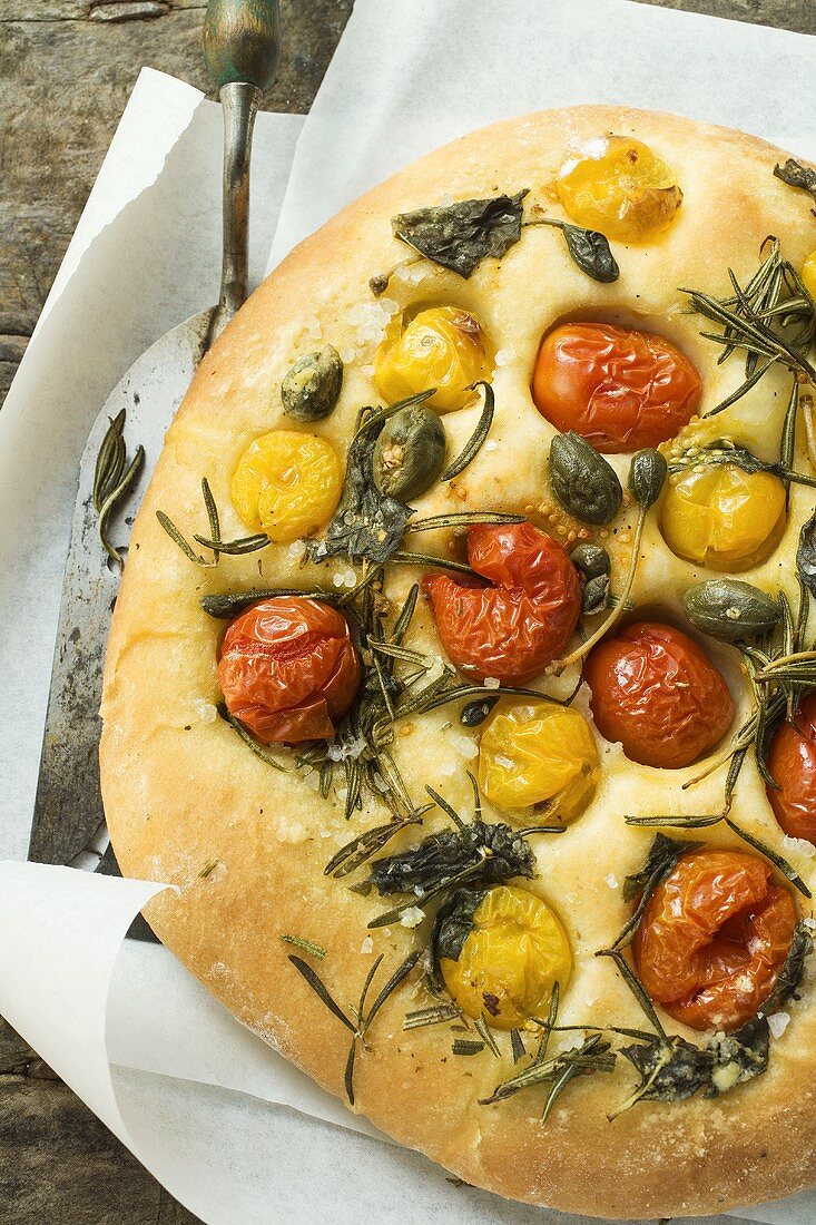 Pizza with cherry tomatoes, capers and rosemary