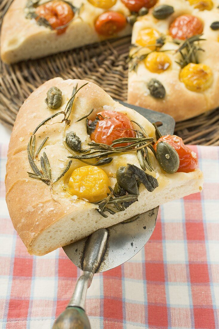 Pizza mit Kirschtomaten, Kapern und Rosmarin (angeschnitten)