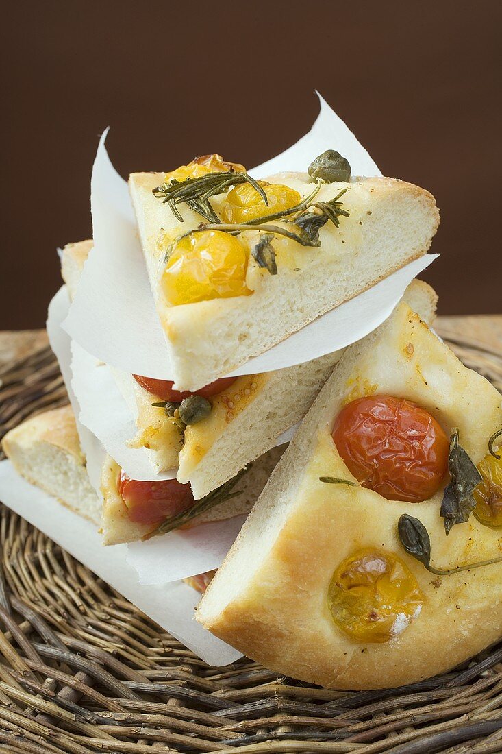 Slices of pizza with cherry tomatoes, capers and rosemary