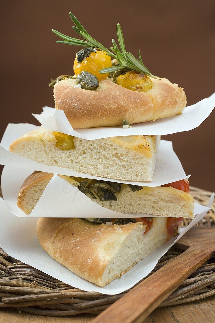 Slices of pizza with cherry tomatoes, capers and rosemary