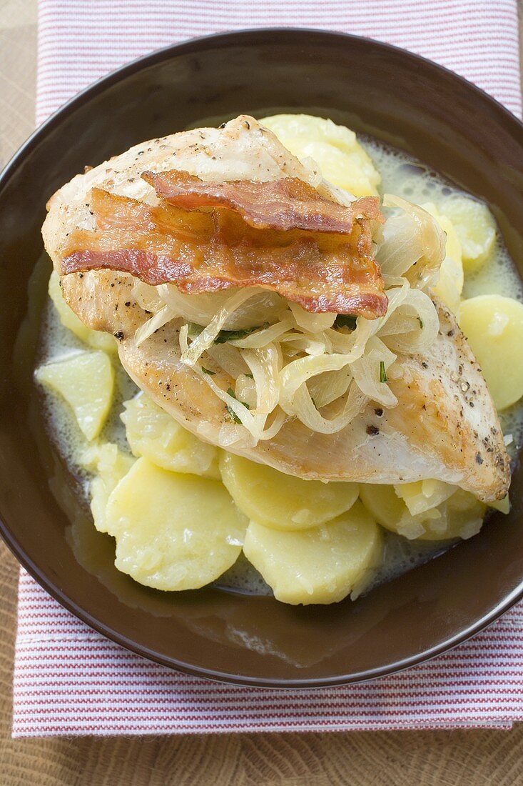 Chicken breast with bacon and onions on potato salad