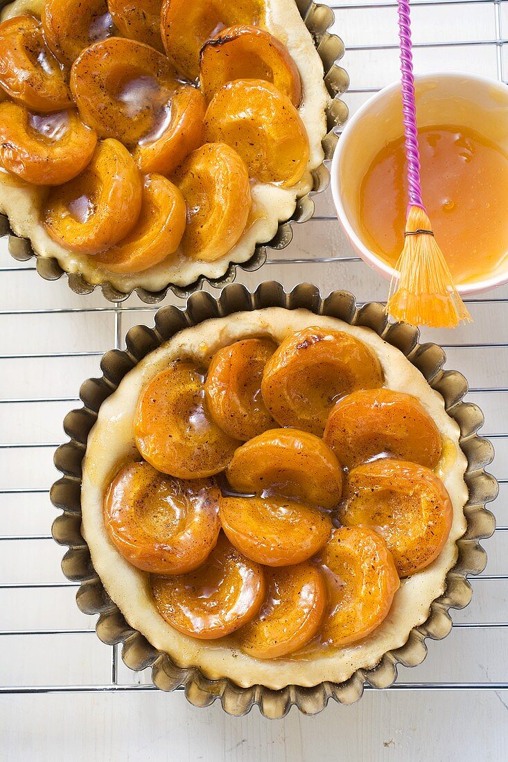 Apricot tarts in baking tins on cake rack