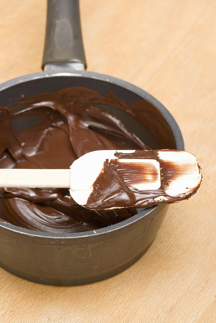 Geschmolzene Schokolade auf Teigschaber und im Kochtopf