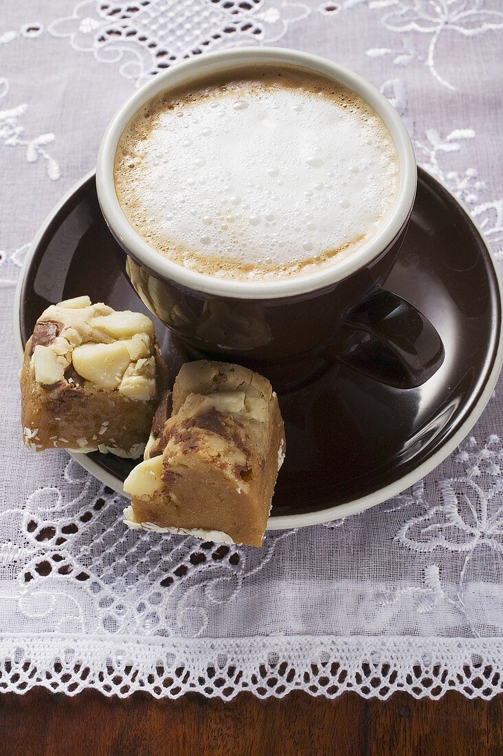 Cappuccino und kleine Stücke Schokokuchen mit Macadamianüssen